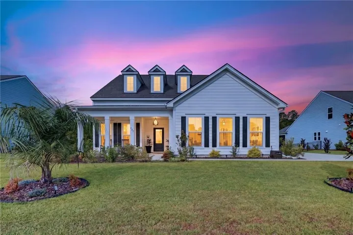 Coastal-inspired architecture featuring a broad front porch, three dormer windows, and a manicured lawn