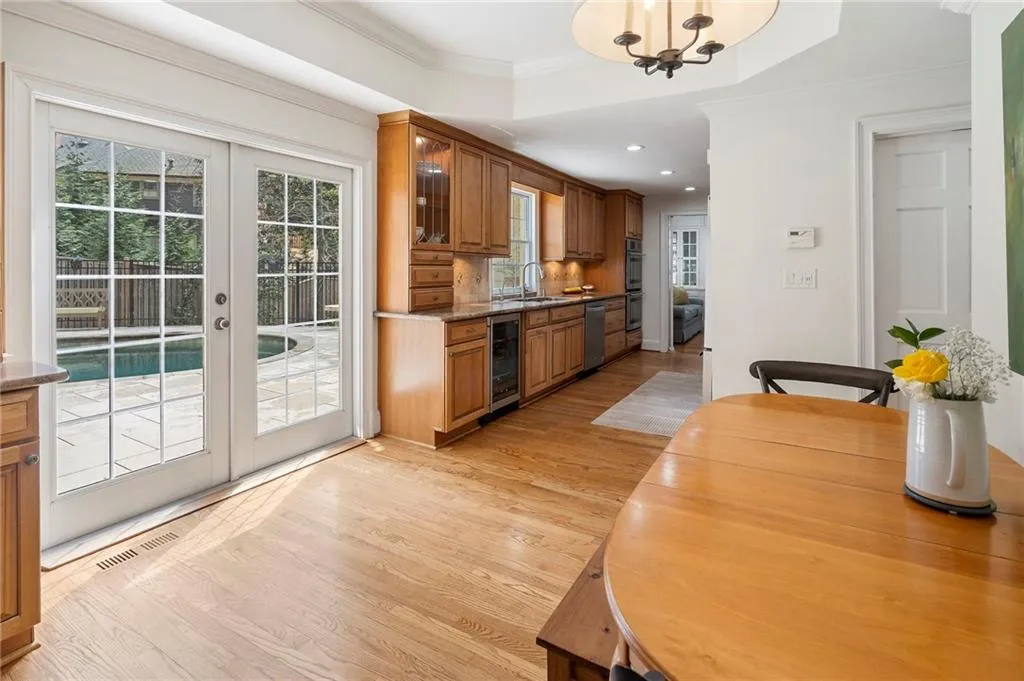 Dining room with french doors, light wood-style floors, beverage cooler, crown molding, and hanging lights
