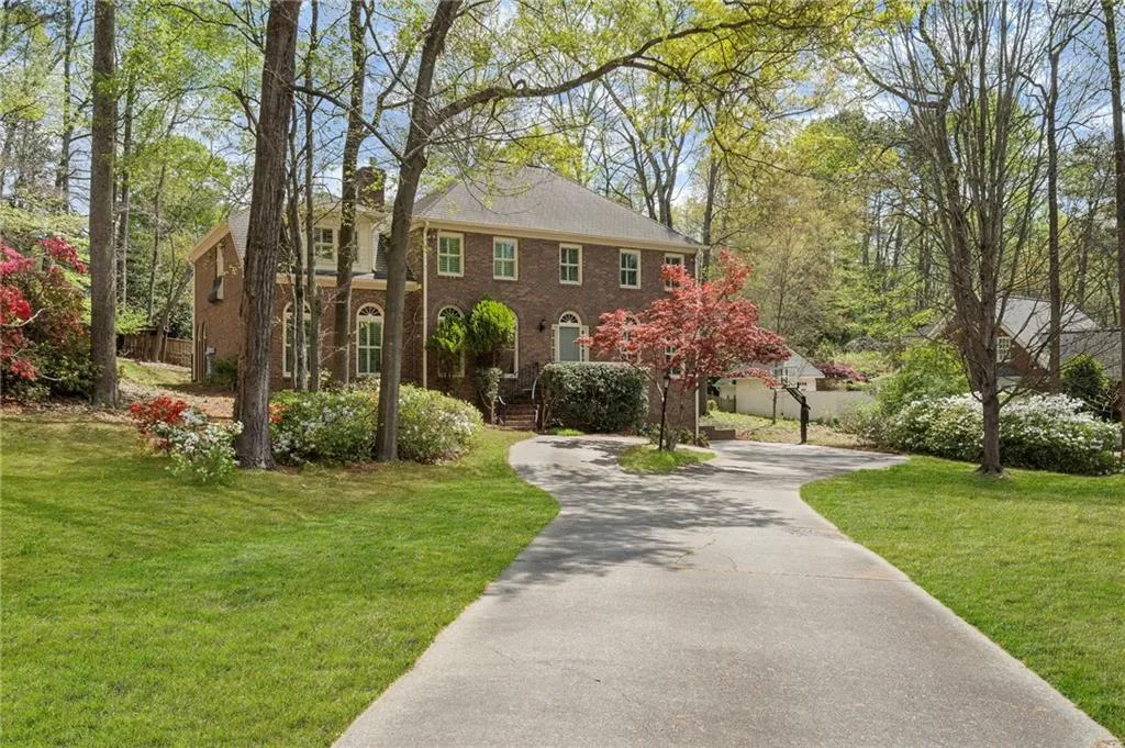 View of front facade with brick siding, a front lawn, and driveway