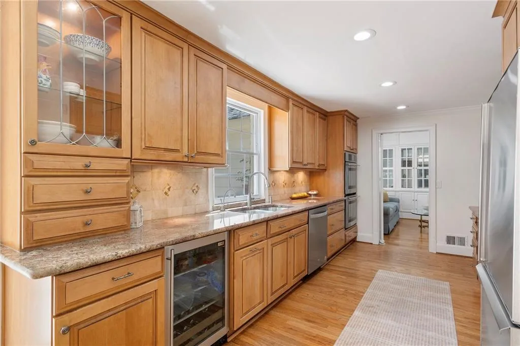 Kitchen featuring wine cooler, glass insert cabinets, stainless steel appliances, backsplash, and light wood-style floors