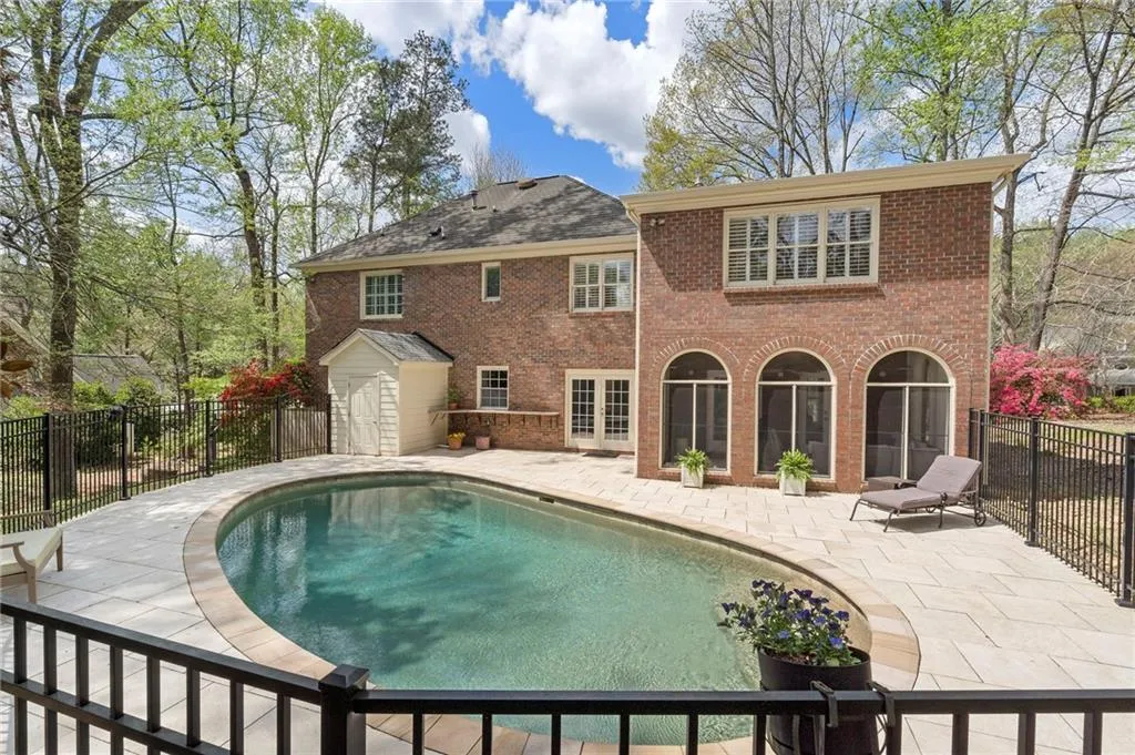 Back of house featuring a fenced backyard, a patio, brick siding, and french doors