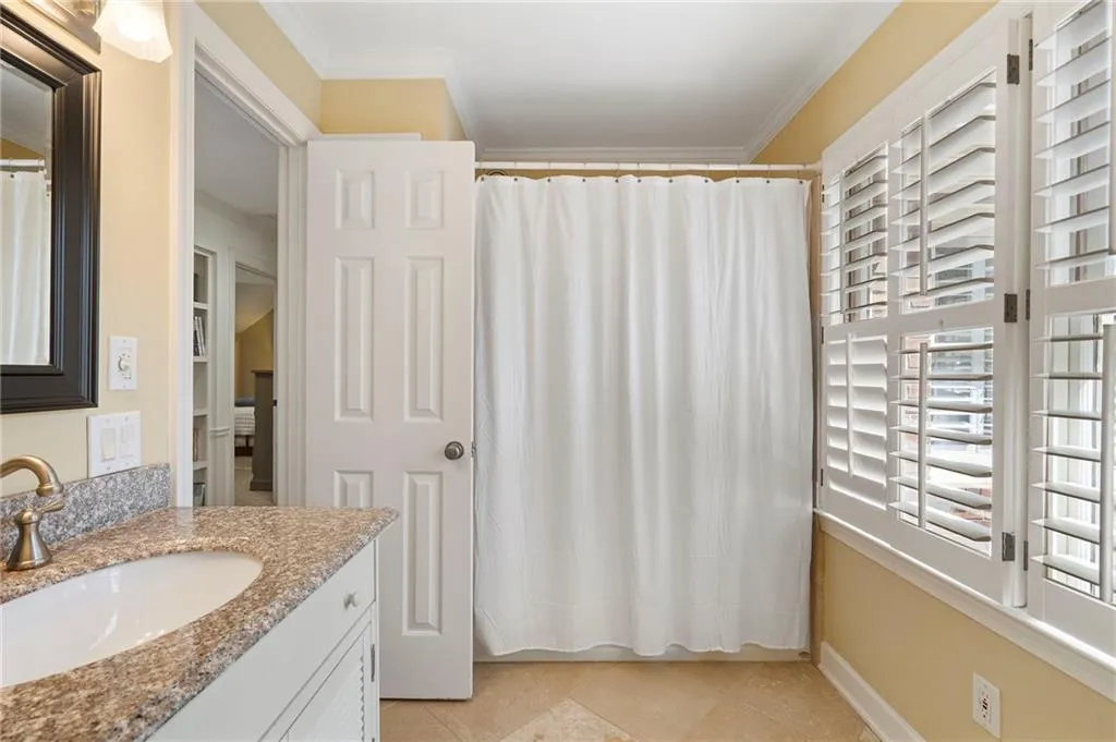 Full bathroom with a shower with curtain, vanity, ornamental molding, and light tile patterned flooring