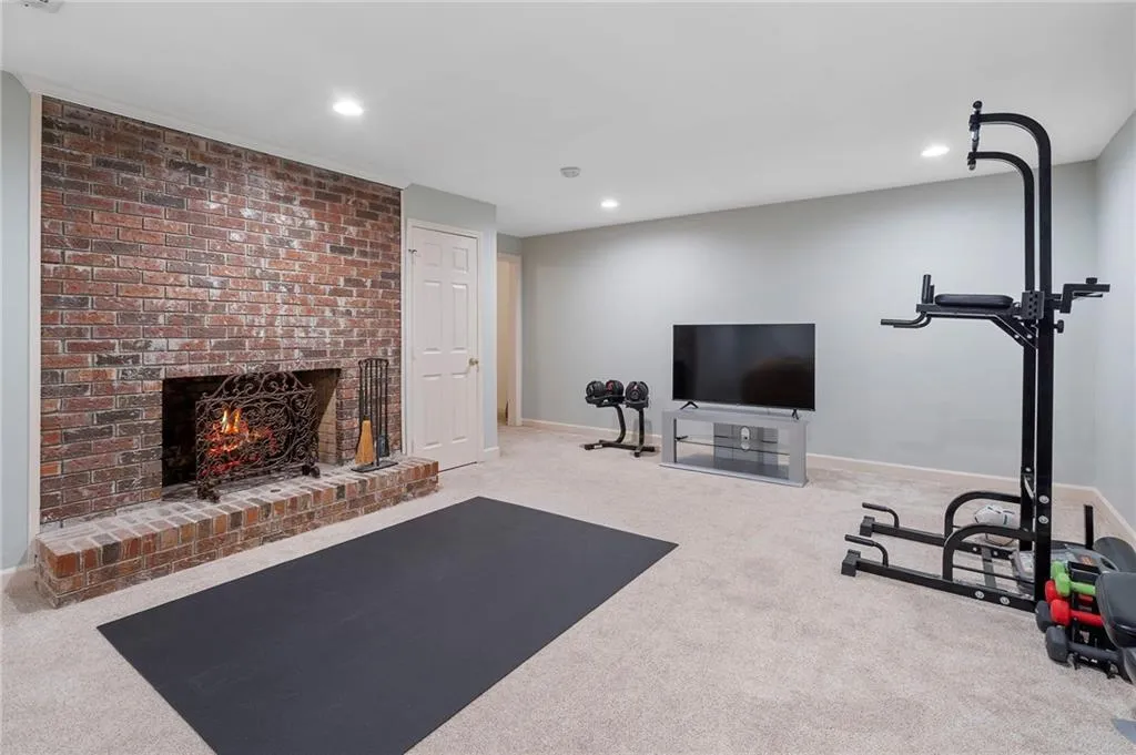 Workout room with light colored carpet, recessed lighting, and a fireplace