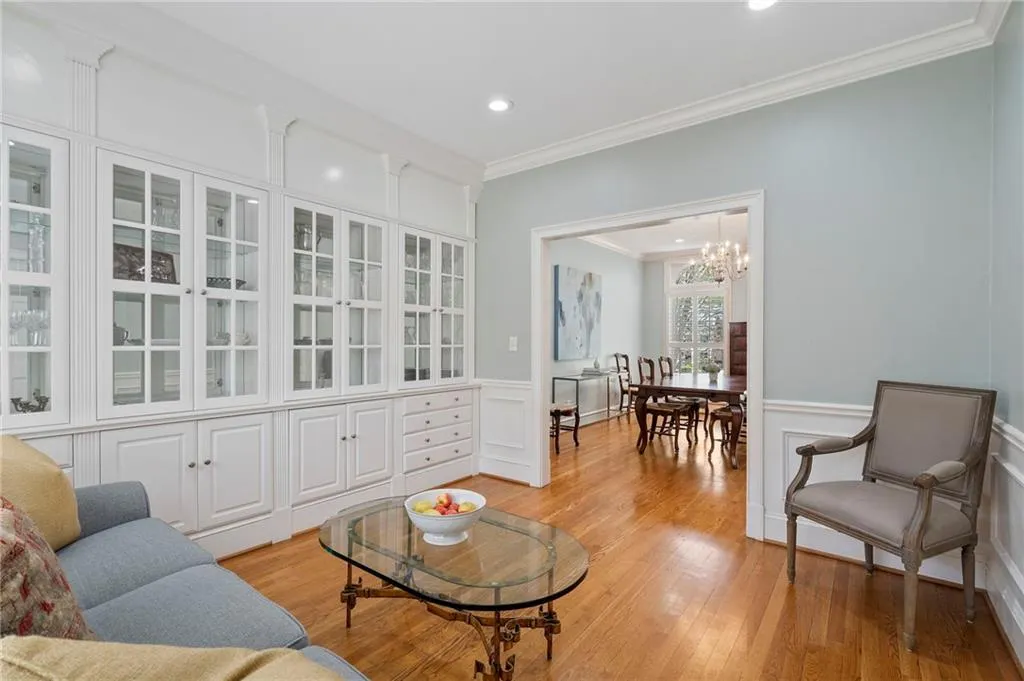 Living area featuring crown molding, light wood finished floors, a wainscoted wall, hanging lights, and a decorative wall