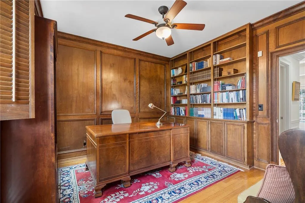 Office with built in features, wooden walls, ceiling fan, a decorative wall, and light wood finished floors