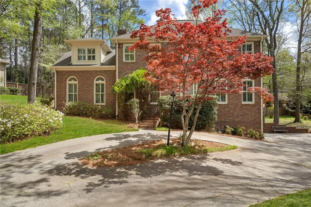 View of front facade with curved driveway, a front lawn, and brick siding