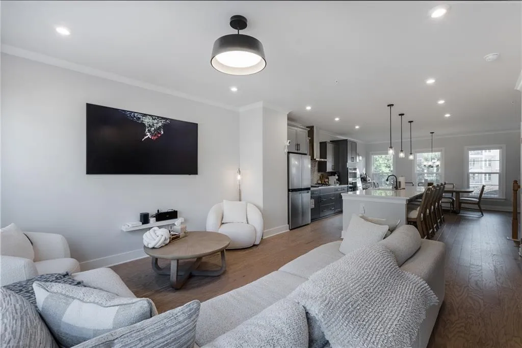 Living room with ornamental molding, wood finished floors, and recessed lighting