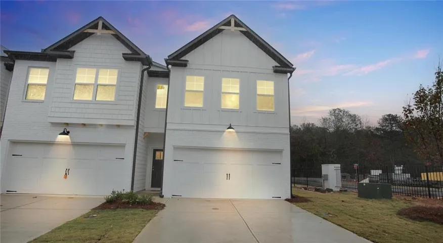 View of front facade with an attached garage, board and batten siding, concrete driveway, and brick siding