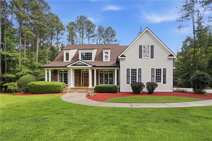 Traditional-style custom craftsman home featuring a covered front porch with white columns, brick accent siding, and multiple dormer windows.