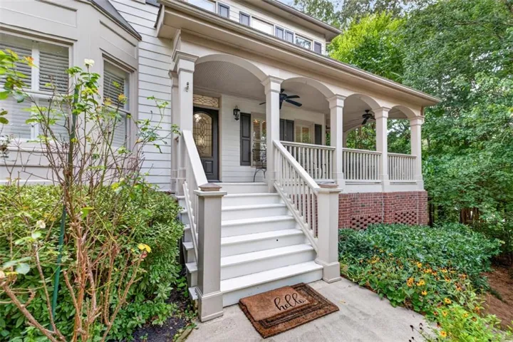 Inviting covered front porch with arched columns, white railings, and twin ceiling fans