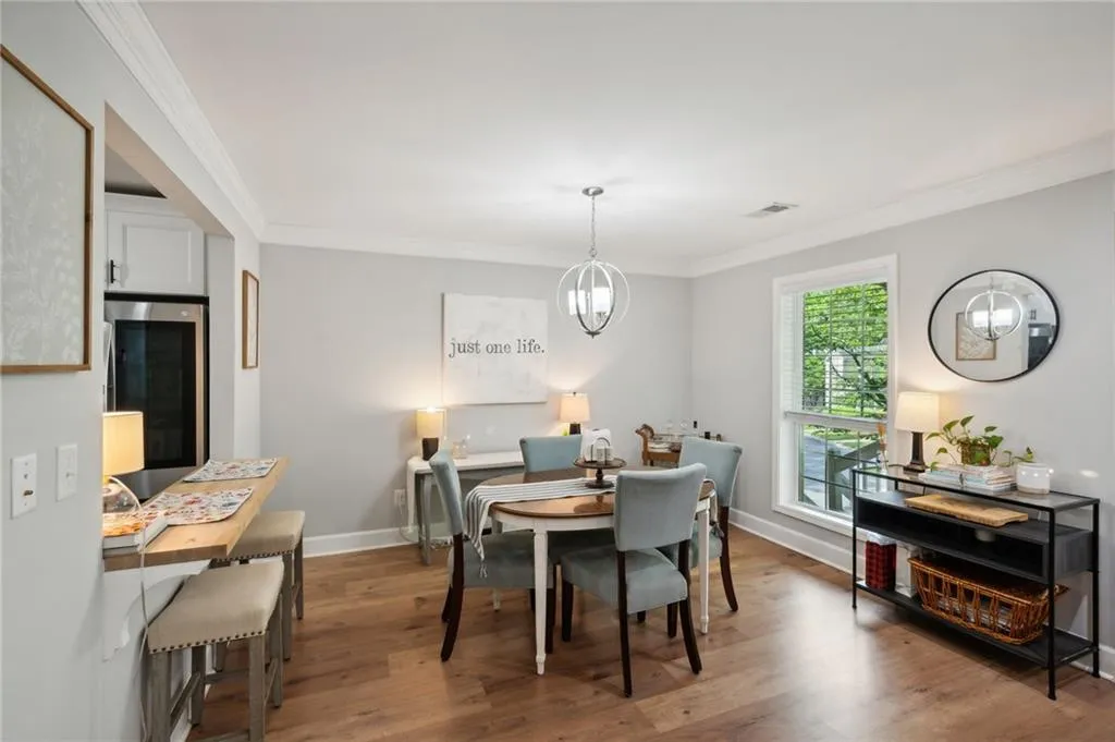 Dining area with a notable chandelier, hardwood / wood-style flooring, and ornamental molding
