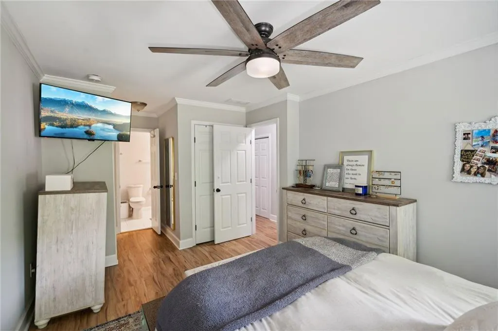 Bedroom featuring ornamental molding, light hardwood / wood-style floors, connected bathroom, and ceiling fan