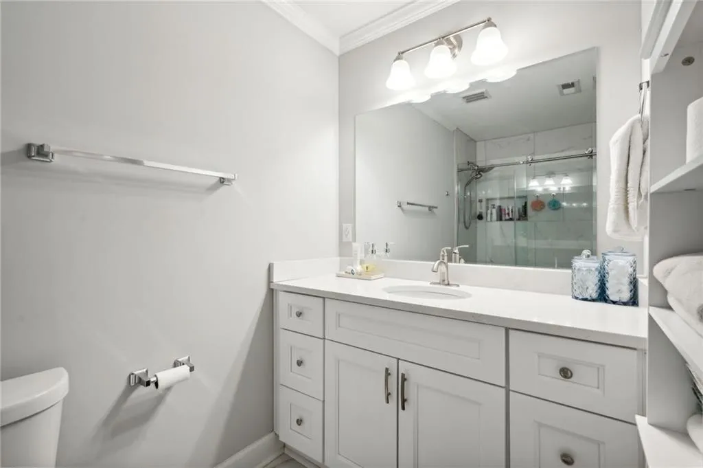 Bathroom featuring ornamental molding, toilet, vanity, and a tile shower