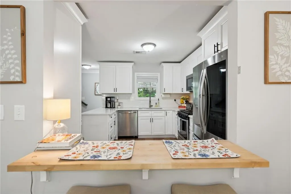 Kitchen featuring appliances with stainless steel finishes, a breakfast bar area, tasteful backsplash, white cabinetry, and sink