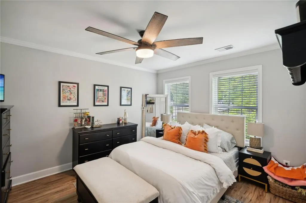 Bedroom with dark hardwood / wood-style flooring, ceiling fan, and crown molding