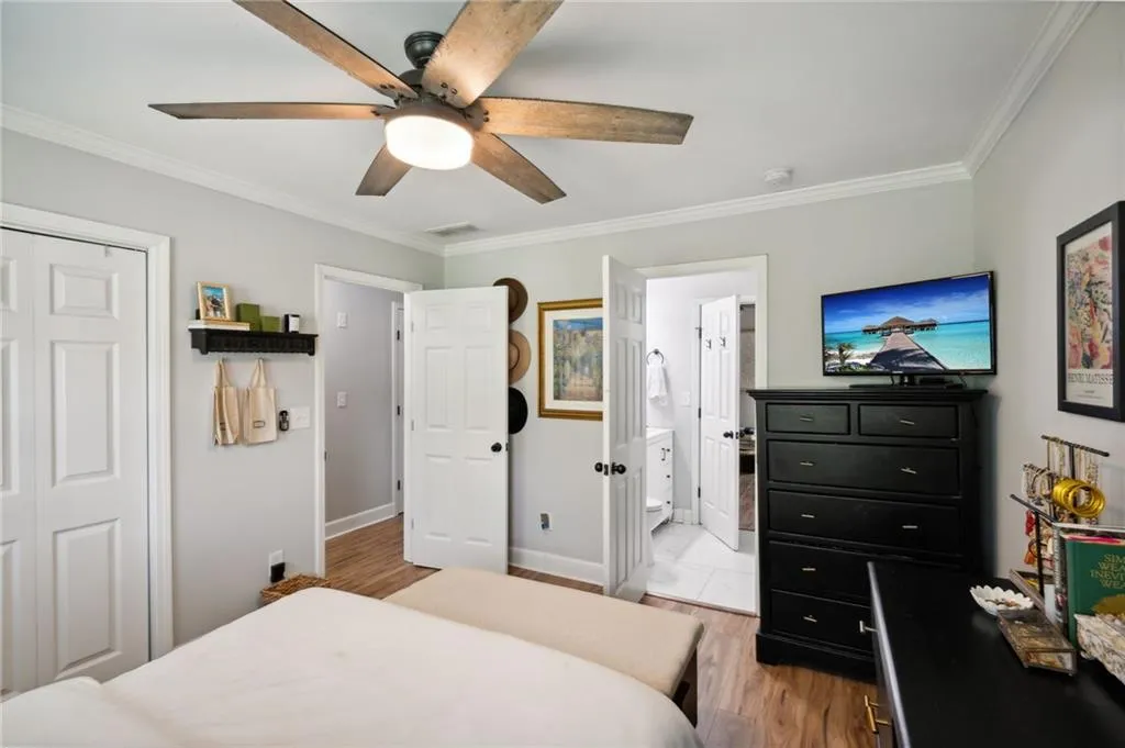 Bedroom with ensuite bathroom, ceiling fan, crown molding, a closet, and light wood-type flooring