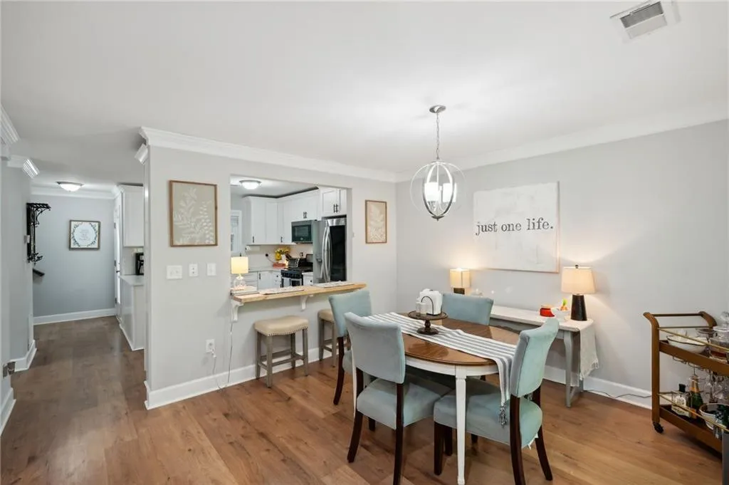 Dining room with crown molding, an inviting chandelier, and hardwood / wood-style floors