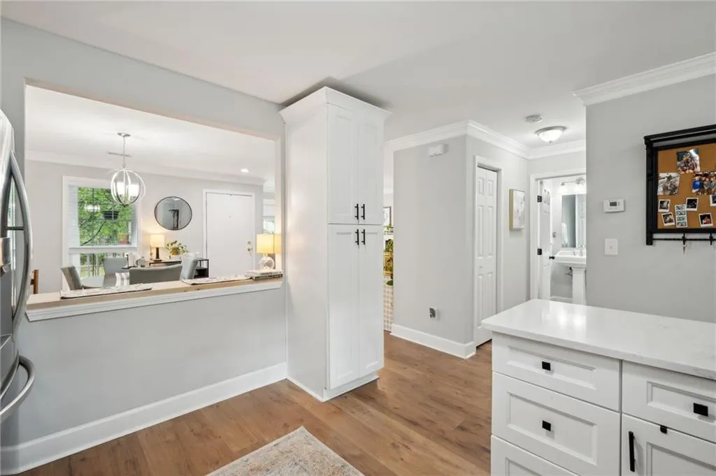 Kitchen with pendant lighting, white cabinets, light hardwood / wood-style flooring, ornamental molding, and an inviting chandelier
