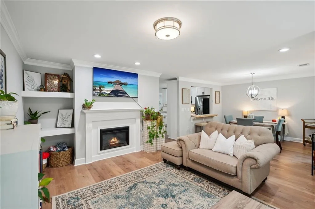 Living room featuring hardwood / wood-style floors, a notable chandelier, and ornamental molding