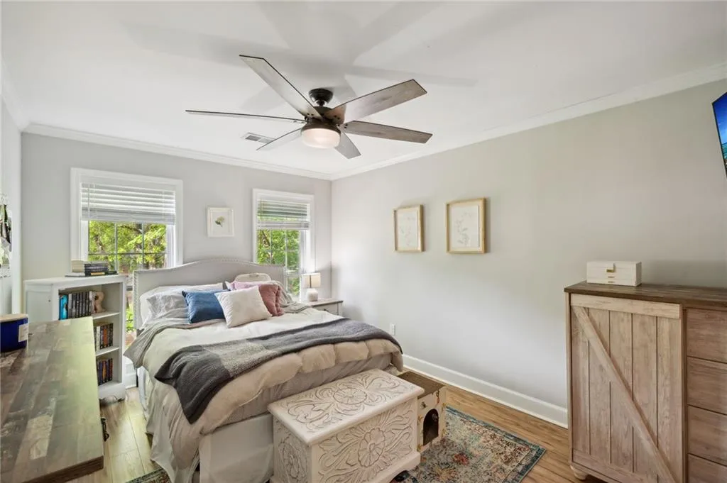 Bedroom with ornamental molding, light hardwood / wood-style floors, and ceiling fan