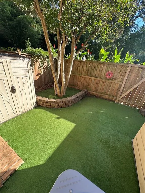 Fenced backyard with a storage unit and an area to practice putting