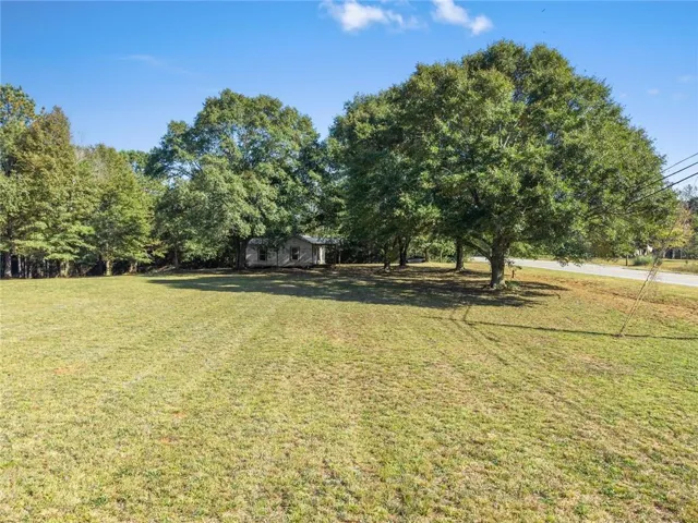 Expansive green space featuring a distant structure and mature trees