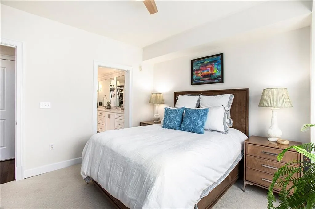 Bedroom with ensuite bathroom, light carpet, and ceiling fan