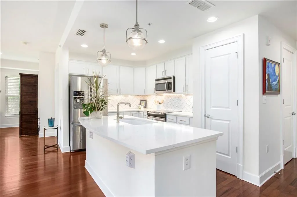 Kitchen with stainless steel appliances, dark hardwood / wood-style flooring, and a center island with sink