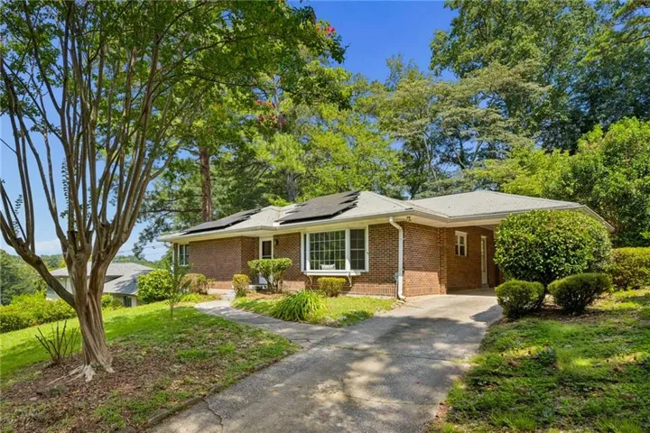 Brick exterior featuring a bay window, covered carport, and mature landscaping