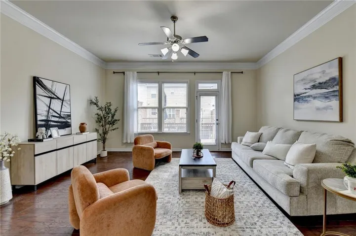 Living area featuring wood-finish flooring, crown molding, and a ceiling fan with integrated lighting