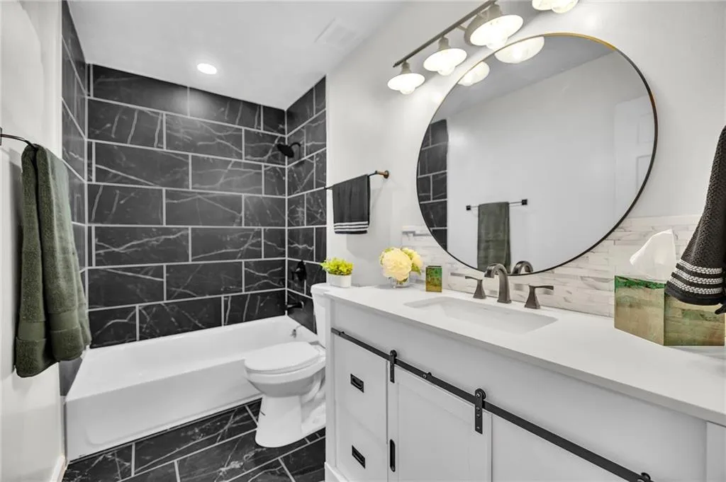 Full bath featuring vanity, shower / bathtub combination, dark marble finish flooring, recessed lighting, and decorative backsplash