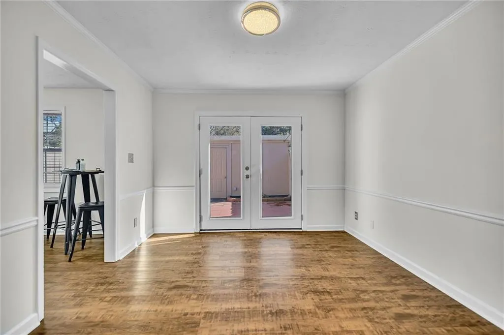 Spare room featuring french doors, wood finished floors, ornamental molding, and plenty of natural light