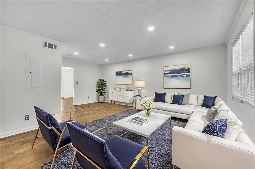 Living room featuring wood finished floors, crown molding, recessed lighting, and electric panel