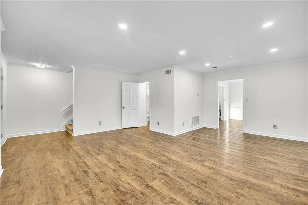 Spare room with ornamental molding, wood finished floors, stairs, and recessed lighting