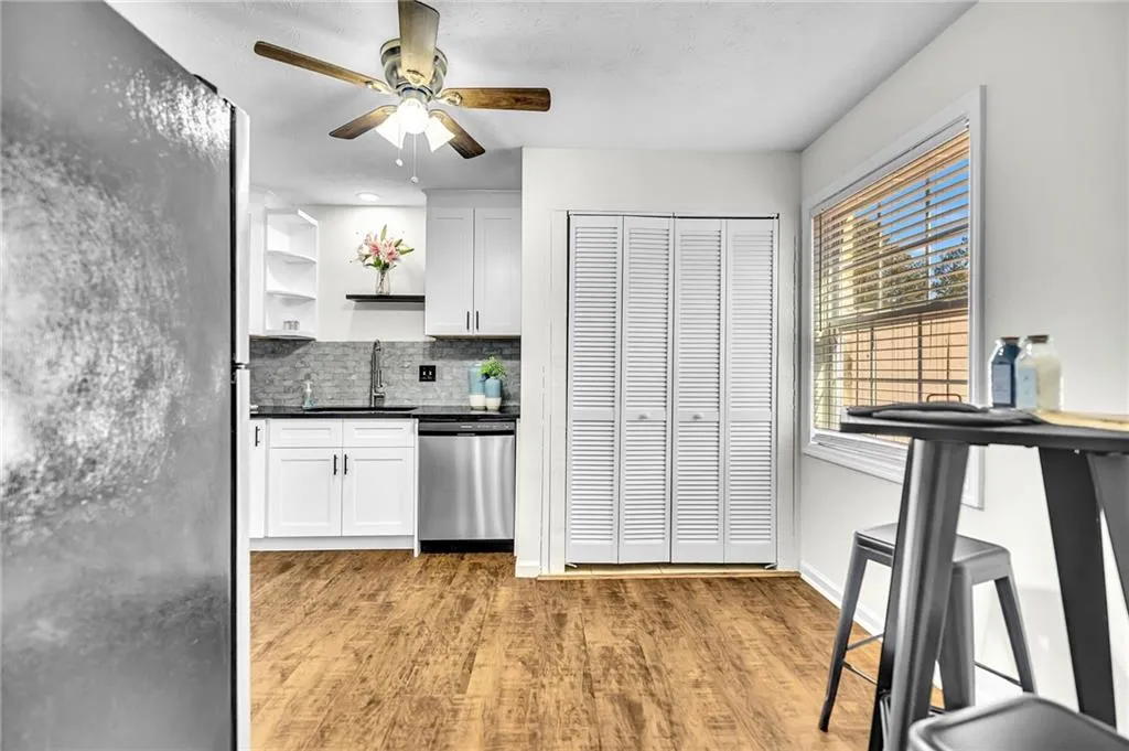 Kitchen featuring decorative backsplash, open shelves, appliances with stainless steel finishes, light wood-type flooring, and white cabinets