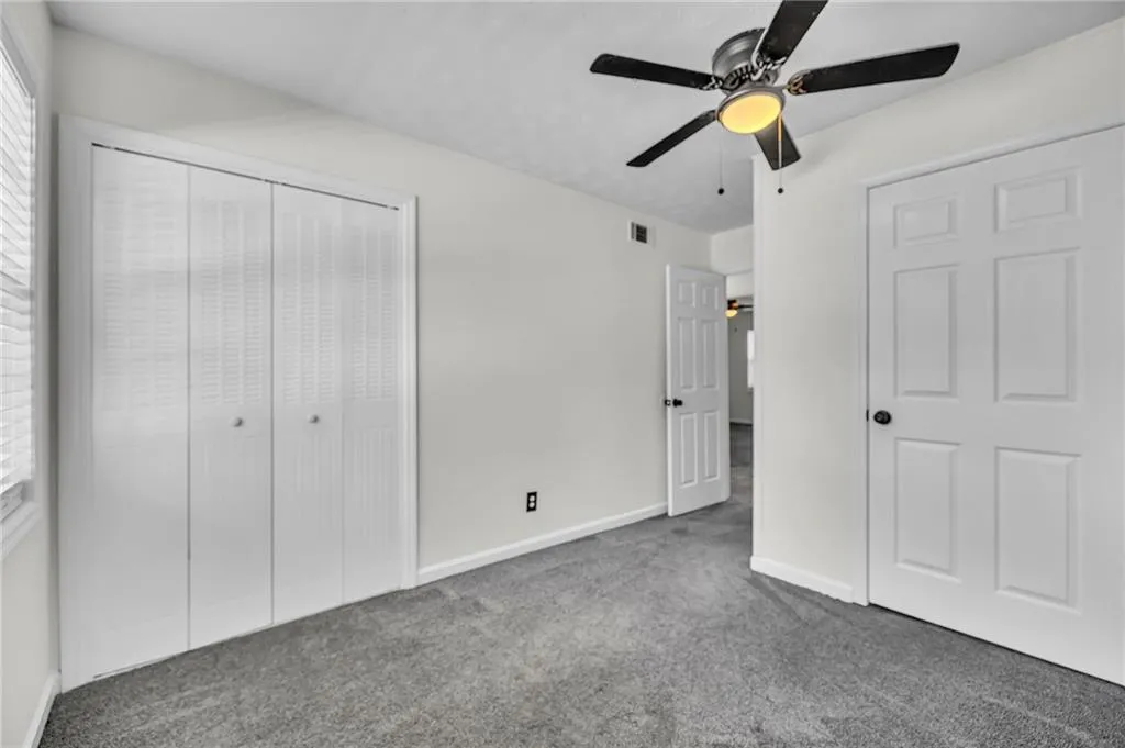 Unfurnished bedroom with multiple windows, carpet, ceiling fan, and a closet