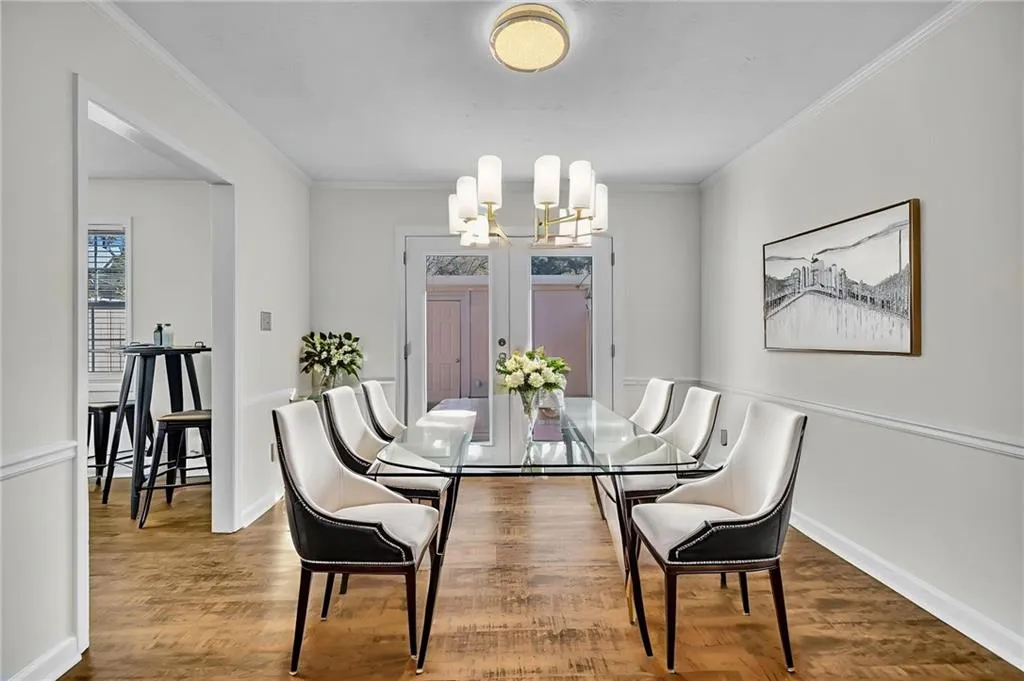 Dining room featuring wood finished floors, ornamental molding, and a chandelier