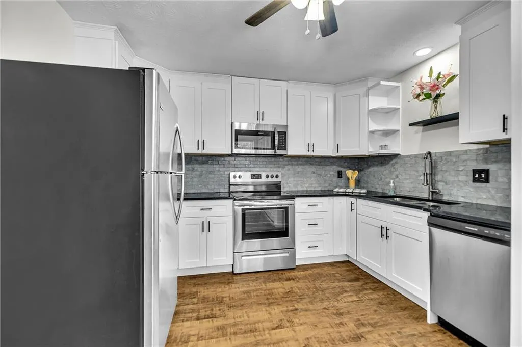 Kitchen featuring open shelves, stainless steel appliances, dark wood-style floors, and white cabinets