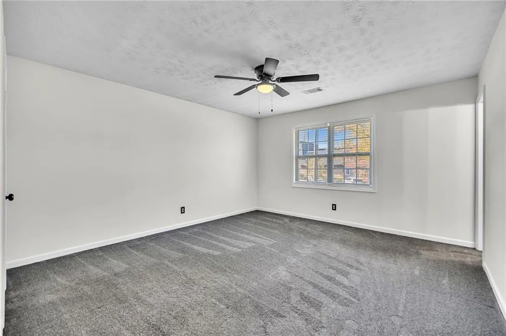 Empty room featuring carpet, a textured ceiling, and a ceiling fan