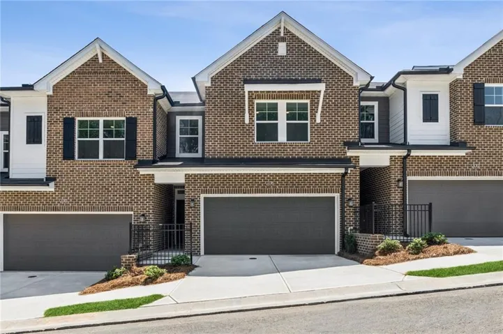 Brick facade with white siding accents, black window shutters, two attached garages, and a paved driveway