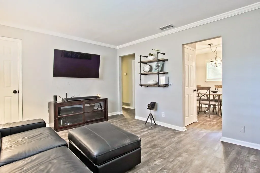 Living area featuring wood finished floors, crown molding, and a chandelier