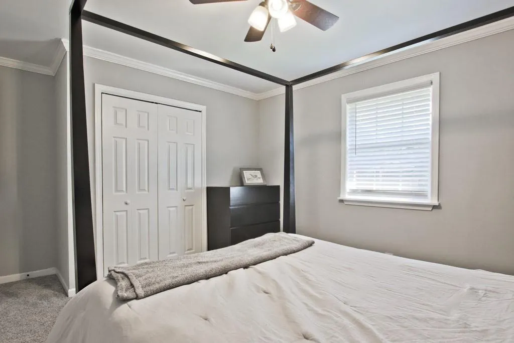Bedroom with crown molding, carpet floors, ceiling fan, and a closet