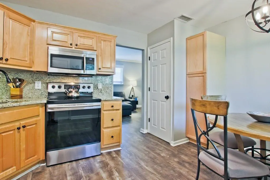 Kitchen featuring appliances with stainless steel finishes, light stone counters, light brown cabinetry, and dark wood finished floors