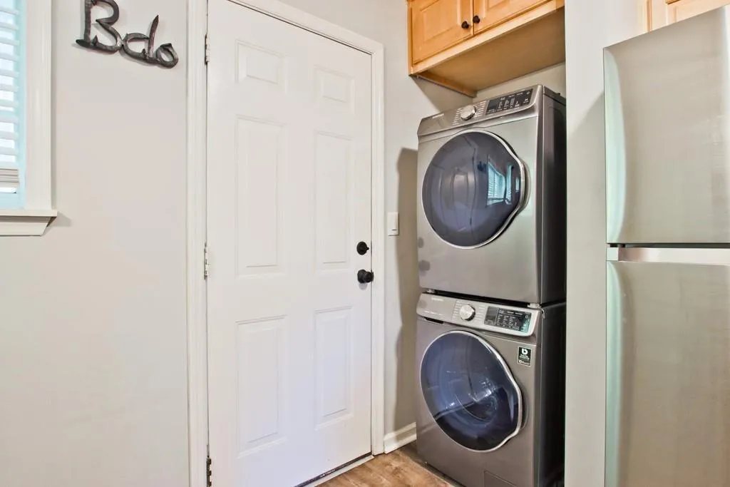 Washroom featuring stacked washing machine and dryer and light wood-style floors