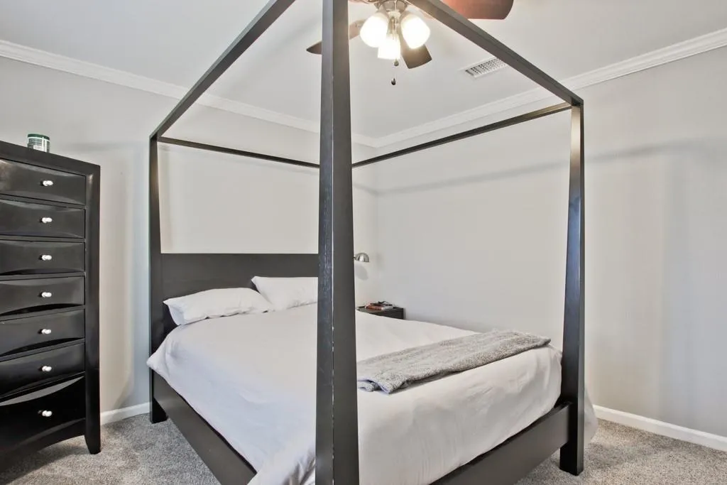 Bedroom with ornamental molding, light carpet, and a ceiling fan