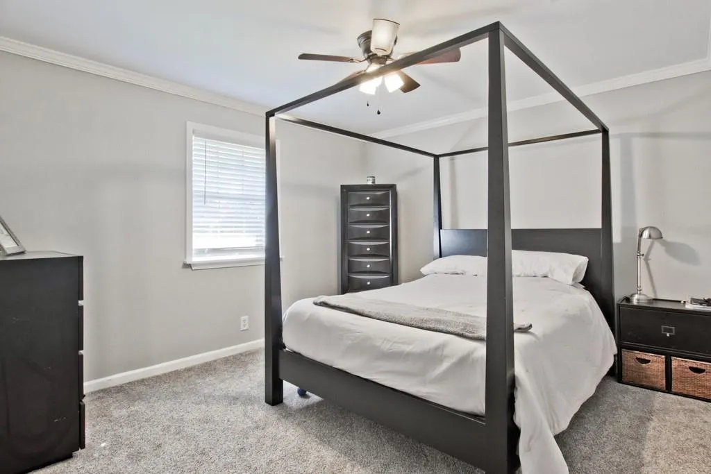 Bedroom with ornamental molding, light colored carpet, and ceiling fan