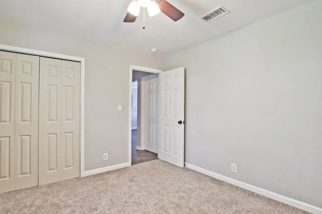 Unfurnished bedroom featuring carpet, a closet, and a ceiling fan