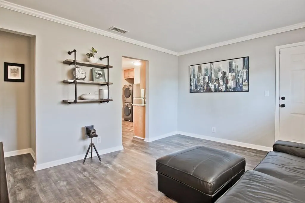 Living room with ornamental molding, wood finished floors, and stacked washer / dryer