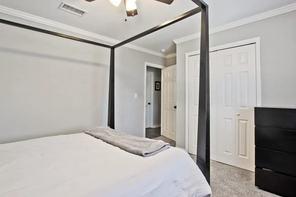 Bedroom with crown molding, light carpet, a ceiling fan, and a closet