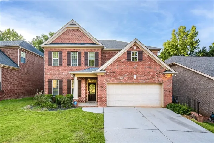 Brick exterior with dark shutters, gabled rooflines, and a two-car garage